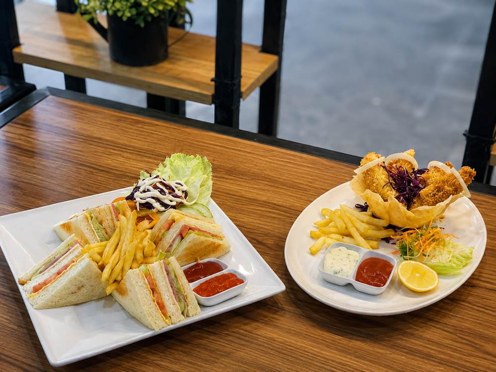 Dua hidangan lengkap dengan kentang goreng dan saus di atas meja kayu di area makan hotel